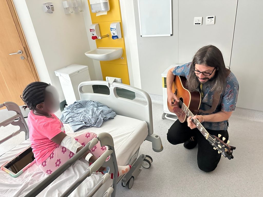 A guitarist playing at a hospital bedside